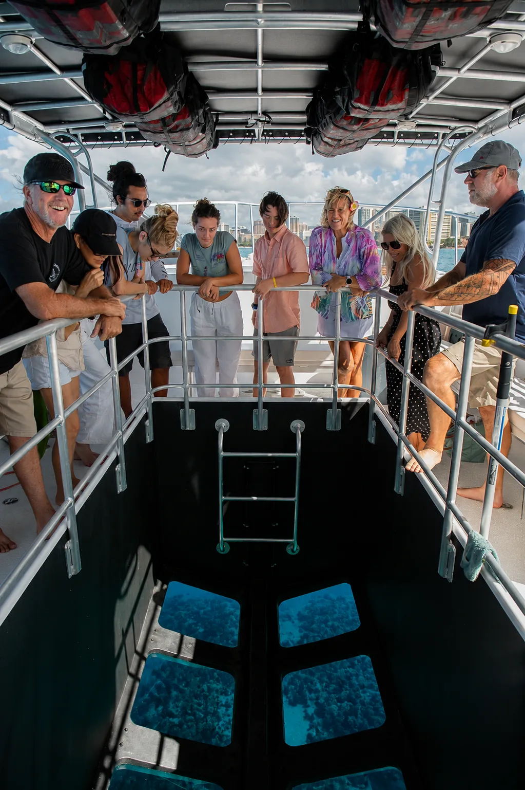 Guests lean on the rail around Illuminate's glass-bottom viewing well.