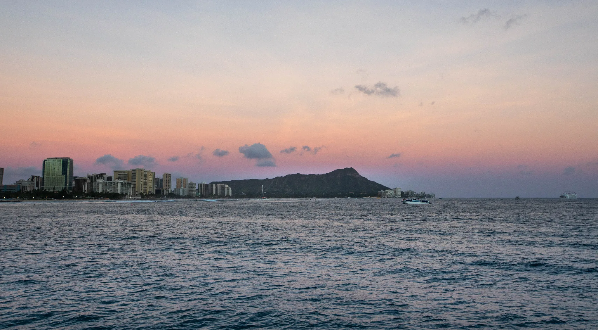 Night view through Illuminate glass panes over the Waikīkī reef, blue glow under low light.